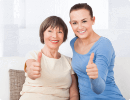 Caregiver and senior woman showing thumbs up