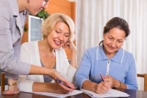 two positive smiling female pensioners signing documents
